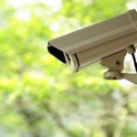 Husband Watches Wife CHASED to Death A security camera mounted outdoors with a blurred green background