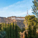 Child Star Vanishes Off-Grid Hollywood sign on hill surrounded by trees and buildings.