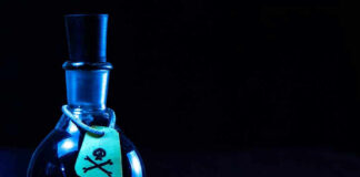 Dark bottle with skull-and-crossbones label on table.
