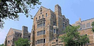 Historic university building with stone facade and surrounding trees