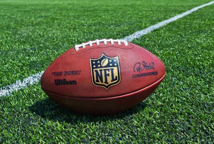 An NFL football resting on a green grass field