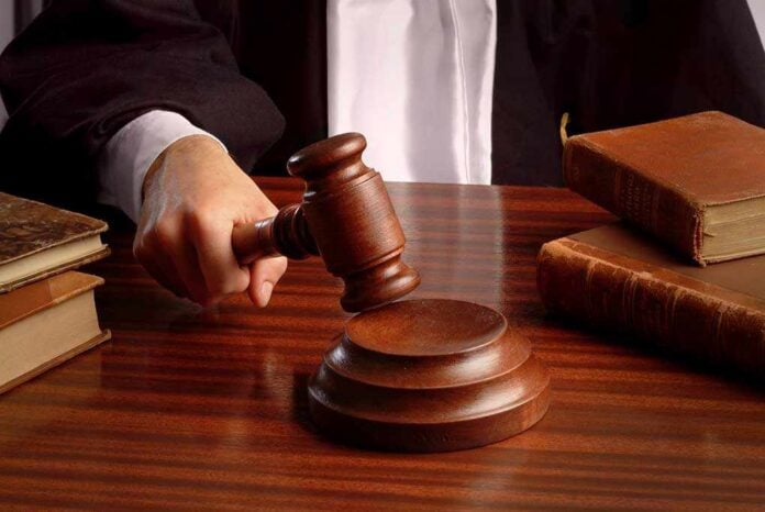 A judges hand holding a gavel over a wooden desk with law books