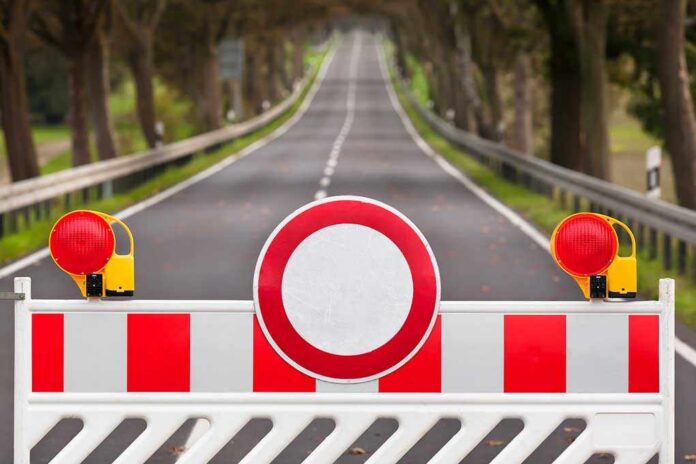 Traffic barrier with a red and white sign blocking a road