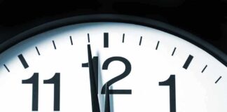 Close-up of a clock showing the time just before noon