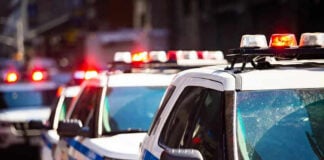 Police cars with flashing lights in line formation.