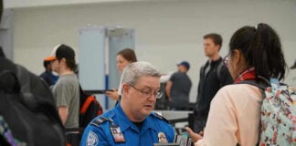 TSA agent checks passengers documents at airport security.