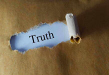 Ripped paper reveals word truth underneath brown surface