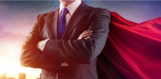 Hero Cops Hauled Before Grand Jury Businessman wearing a cape, standing confidently.