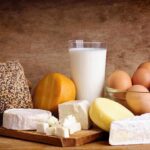 Assorted dairy products including cheese, milk, and eggs on a wooden surface