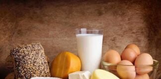 Assorted dairy products including cheese, milk, and eggs on a wooden surface