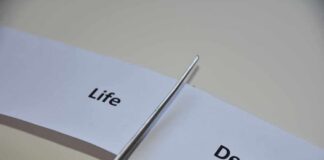 Scissors cutting a paper strip labeled 'Life' and 'Death'