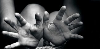 Two hands reaching out, bound by rope in a black and white image