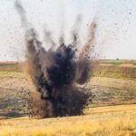 A large explosion creating a dark smoke cloud in a rural landscape