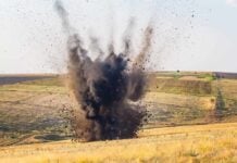 A large explosion creating a dark smoke cloud in a rural landscape