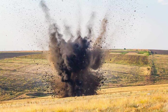 A large explosion creating a dark smoke cloud in a rural landscape