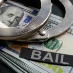 Handcuffs resting on a stack of cash with a 'BAIL' label