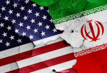 Cracked American and Iranian flags painted on a wall.