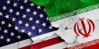 Cracked American and Iranian flags painted on a wall.