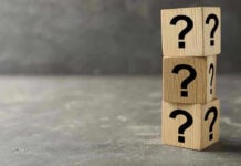 Three wooden blocks with black question marks stacked.