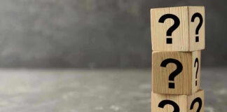 Three wooden blocks with black question marks stacked.