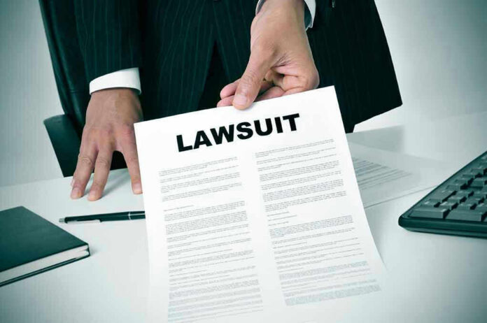 189871757 Person holding a document titled LAWSUIT in office.