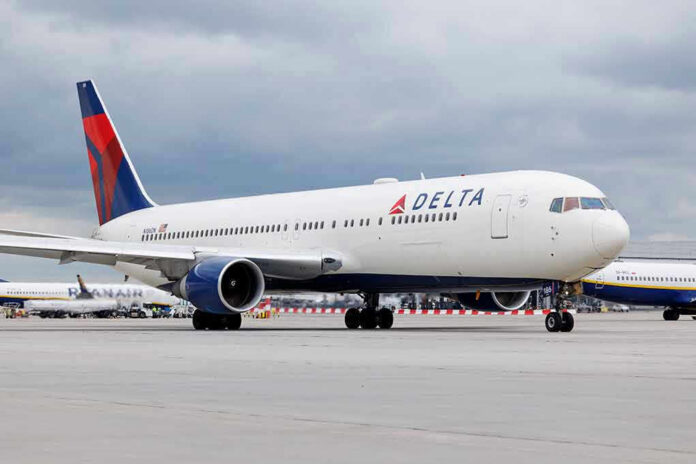 2305553471 Delta Airlines airplane on airport runway, cloudy sky.