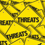 Yellow warning signs with the word THREATS.