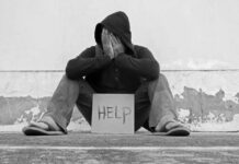 Person sitting holding sign that says help