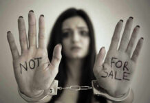 Handcuffed woman shows NOT FOR SALE on her palms.