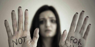 Handcuffed woman shows NOT FOR SALE on her palms.