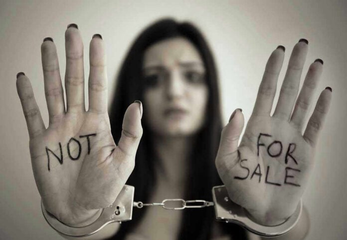 Handcuffed woman shows NOT FOR SALE on her palms.