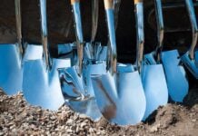 A collection of shiny metal shovels with wooden handles arranged on the ground