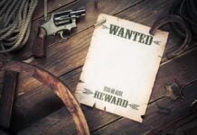 ISIS KILL ORDER Issued on PROMINENT Activist A vintage wanted poster alongside a revolver and rope on a wooden table