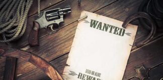 A vintage wanted poster alongside a revolver and rope on a wooden table