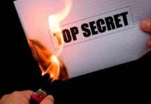 A hand holding a lighter igniting a paper labeled TOP SECRET as it catches fire