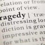 Close-up of the word 'Tragedy' in a dictionary with its definition