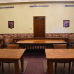 AI Threat Looms: Pope Sounds The Alarm! Empty courtroom with wooden tables, chairs, and a door.