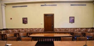 AI Threat Looms: Pope Sounds The Alarm! Empty courtroom with wooden tables, chairs, and a door.