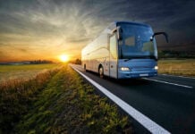 Bus driving on a road at sunset.