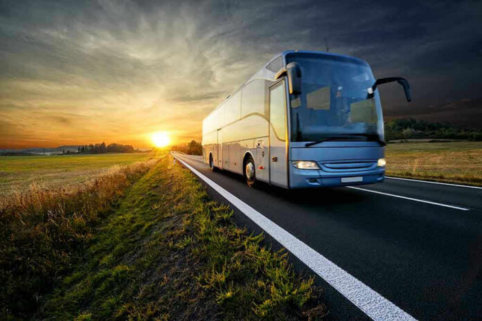 1345741577 Bus driving on a road at sunset.