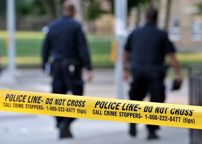 Police officers walking past caution tape at a crime scene
