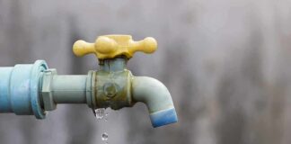 Who’s REALLY Draining America Dry? Close-up of a dripping outdoor water faucet