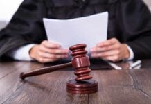 A judge holding documents with a gavel in the foreground