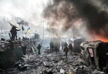 A chaotic protest scene with smoke, fire, and people holding flags
