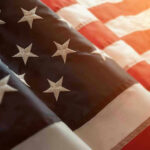 Media Spin: A Simple Flag Video Became a Culture War Overnight Close-up of American flag with sunlit background.