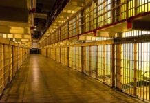 Empty hallway between rows of prison cells.