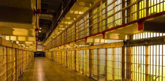 Empty hallway between rows of prison cells.