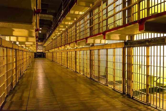 1231860007 Empty hallway between rows of prison cells.