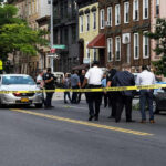 International Hunt Ends With British Doctor’s Arrest Police gathered at an urban crime scene.