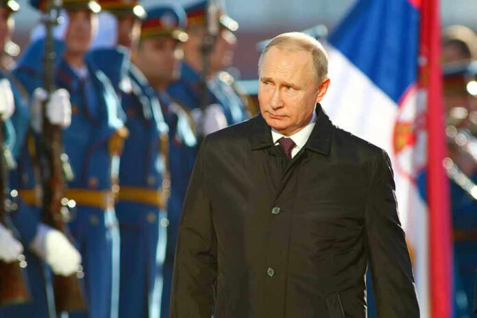 1468367888 Man in black coat with soldiers in background.